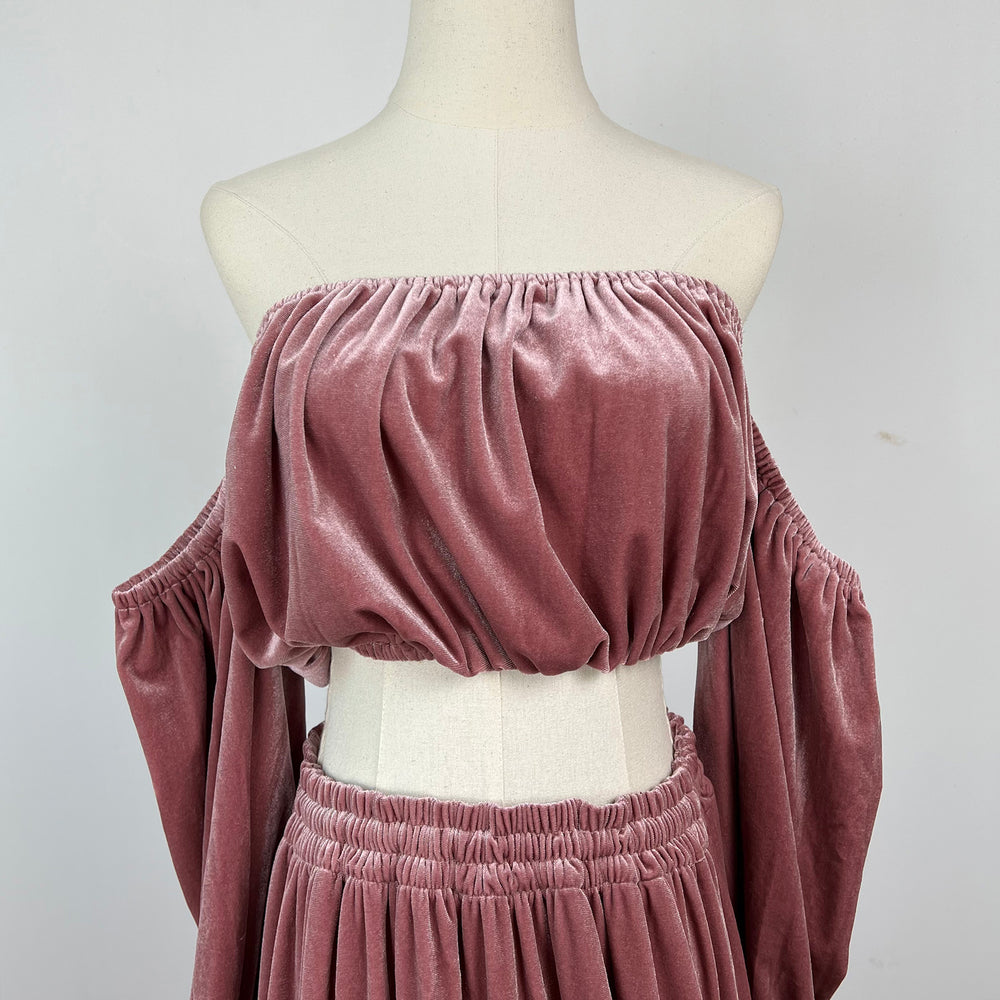 A mannequin displays a close-up of Belisama dress velvet off-shoulder top and floor-length skirt. The two-piece outfit has a ruffled skirt hem.
