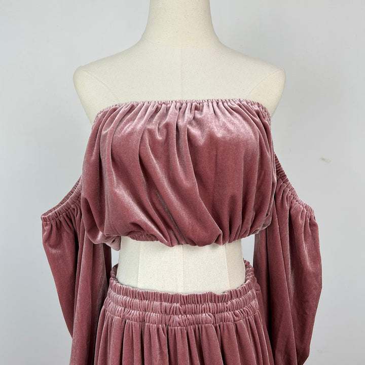 A mannequin displays a close-up of Belisama dress velvet off-shoulder top and floor-length skirt. The two-piece outfit has a ruffled skirt hem.