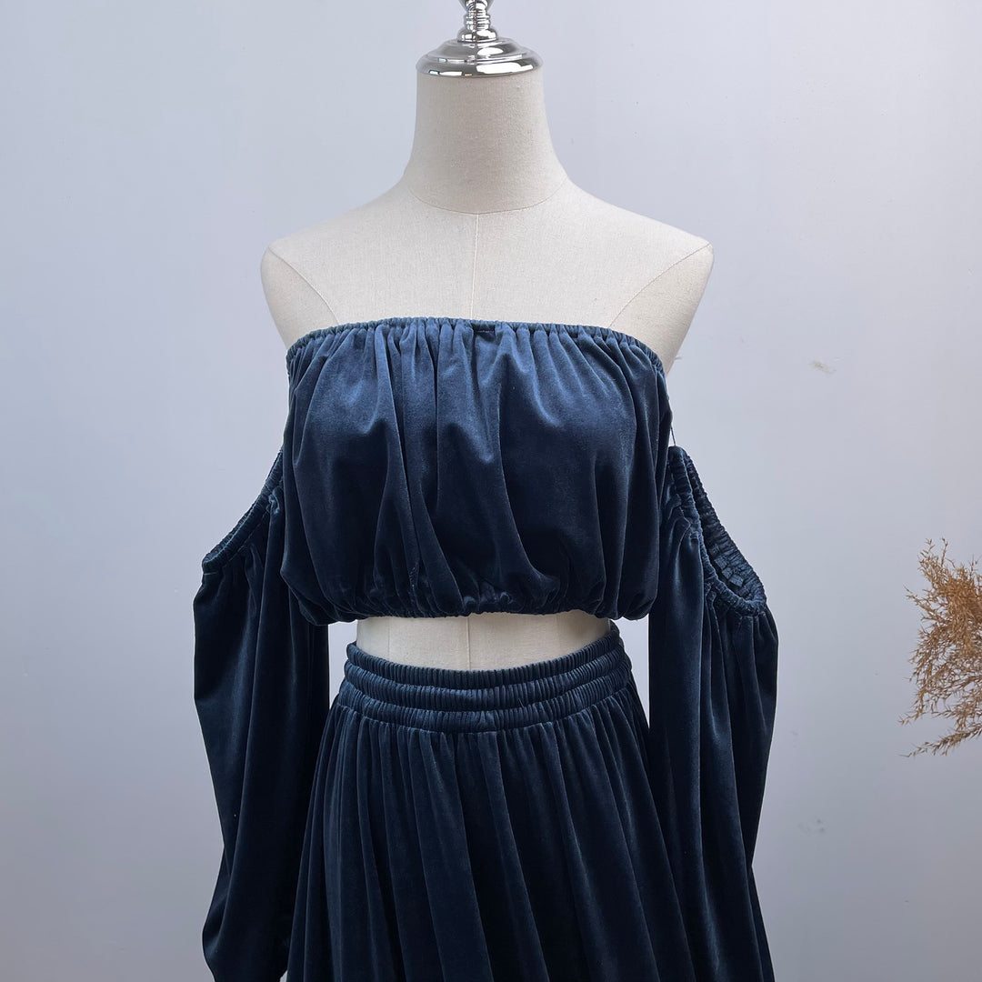 A mannequin displays a close-up of Belisama dress velvet off-shoulder top and floor-length skirt. The two-piece outfit has a ruffled skirt hem.
