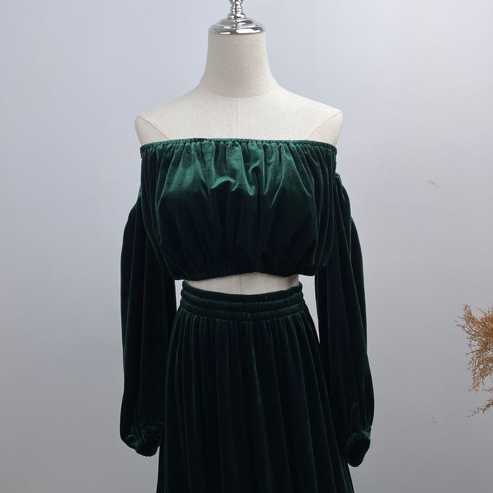 A mannequin displays a close-up of Belisama dress velvet off-shoulder top and floor-length skirt. The two-piece outfit has a ruffled skirt hem.