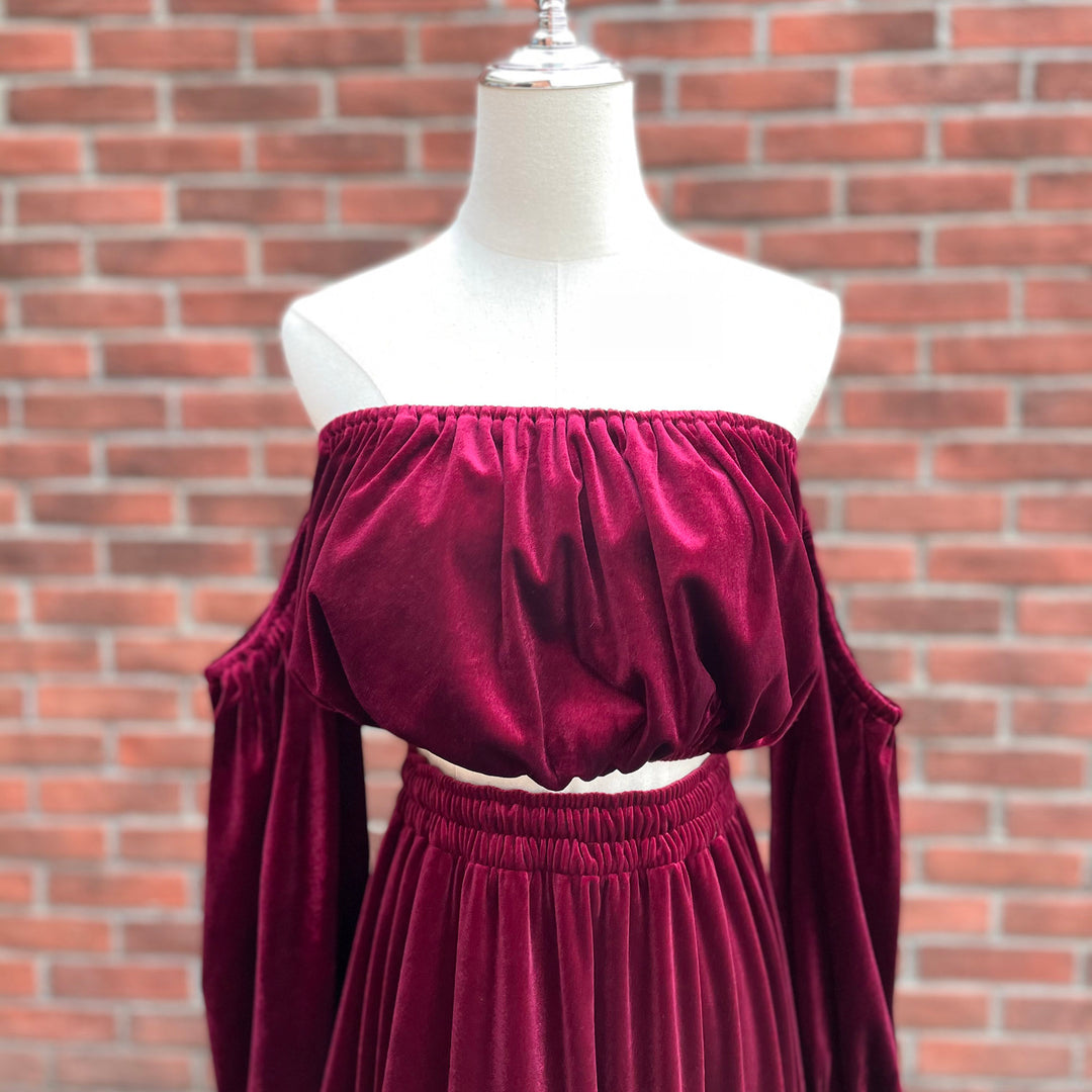 A mannequin displays a close-up of Belisama dress velvet off-shoulder top and floor-length skirt. The two-piece outfit has a ruffled skirt hem.