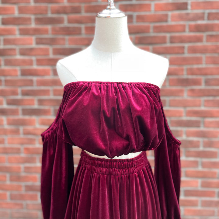A mannequin displays a close-up of Belisama dress velvet off-shoulder top and floor-length skirt. The two-piece outfit has a ruffled skirt hem.