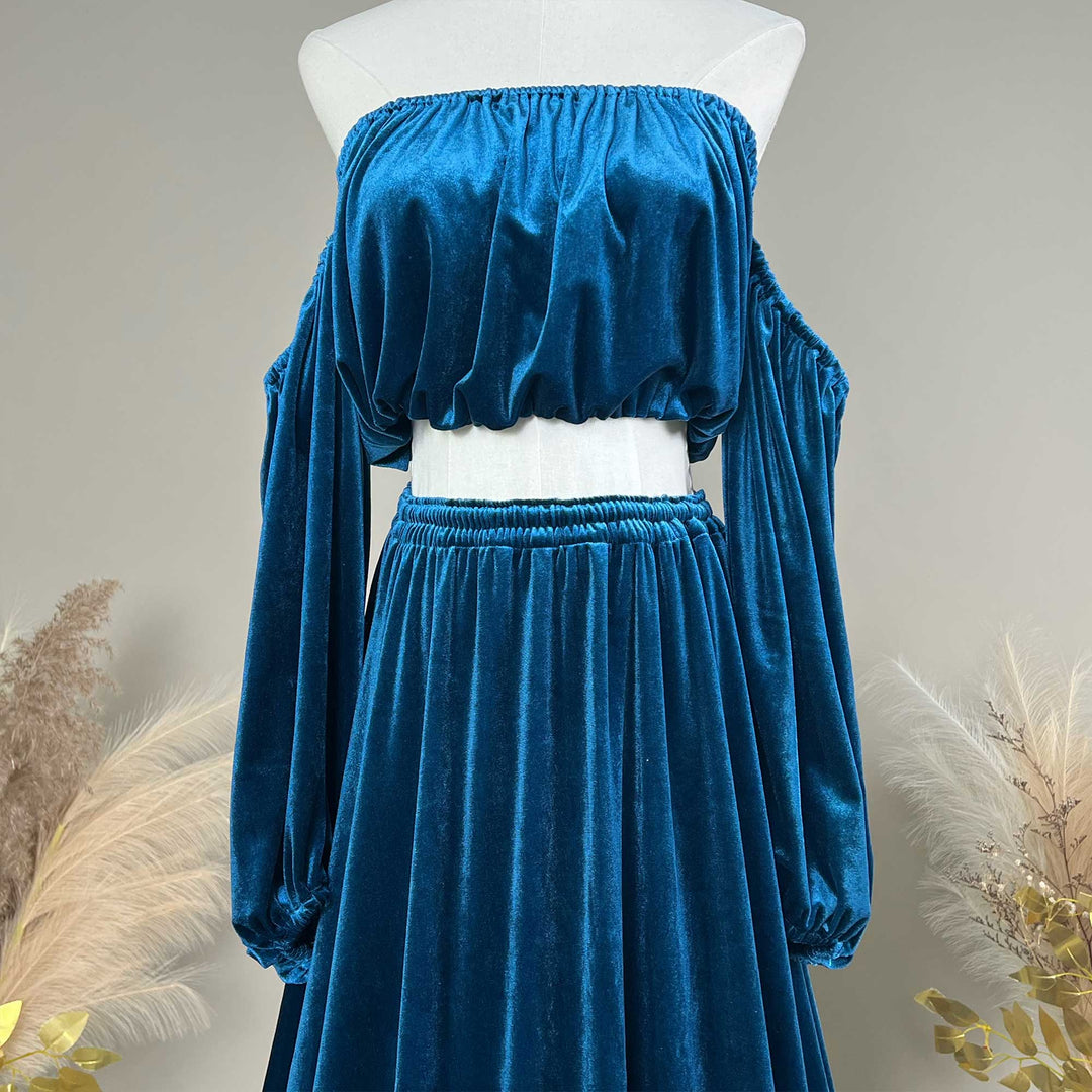 A mannequin displays a close-up of Belisama dress velvet off-shoulder top and floor-length skirt. The two-piece outfit has a ruffled skirt hem.