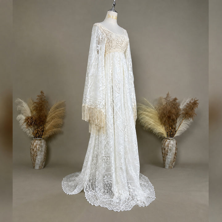 A beige lace gown with fringed cuffs is displayed on a mannequin.
