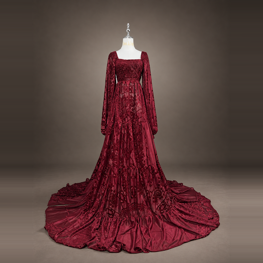 A Calypso red wine long sleeve dress on a mannequin facing forward, train spread on the floor.