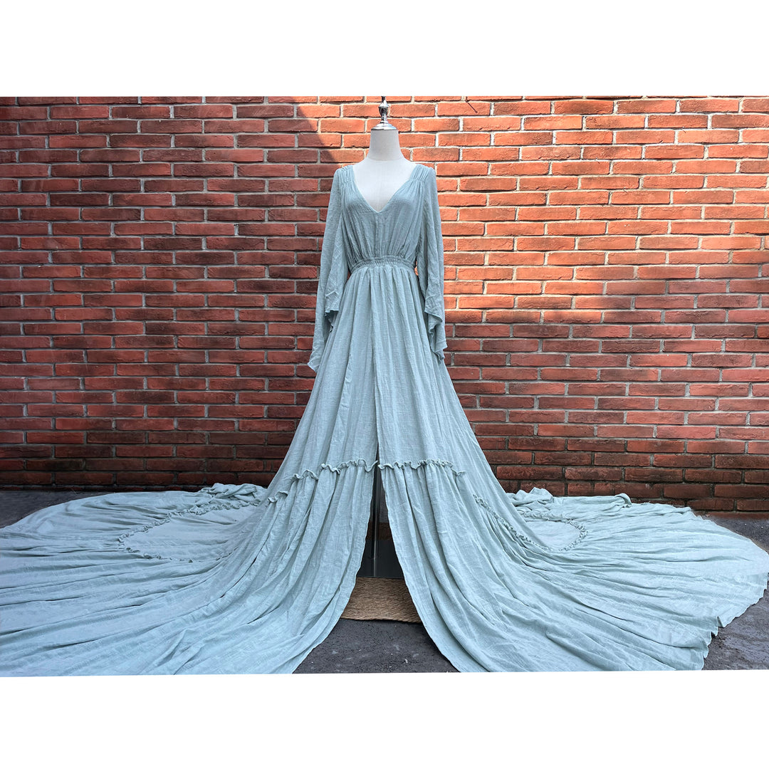 A light blue Daphne long-sleeved V-neck gown is displayed on a mannequin.The dress features a high front slit and its hem and train are spread out on the wooden floor.